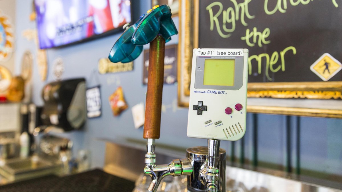 A close view of an old Nintendo Game Boy, with beer taps in the background.