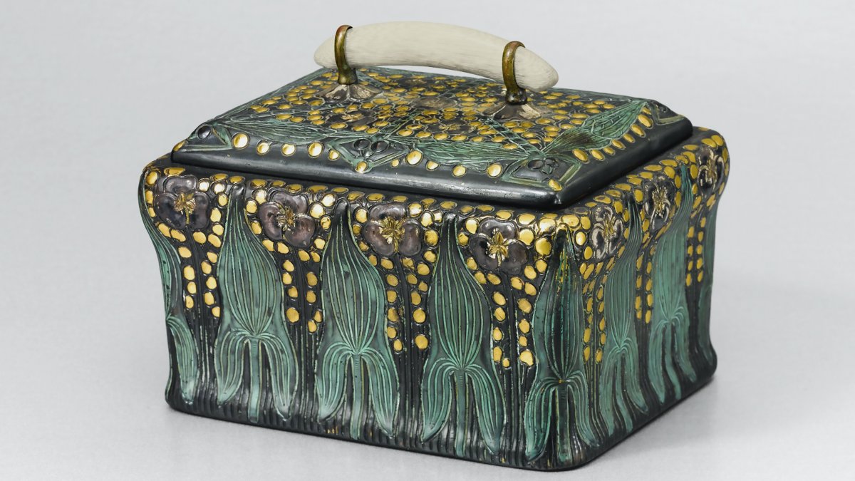 A small black ceramic box that is hand-painted with green and gold accents.