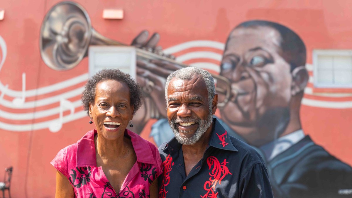The Brayboys, owners of Chef's Creole Cafe, sit in front of their restaurant, which has a mural of Louis Armstrong on its outer wall