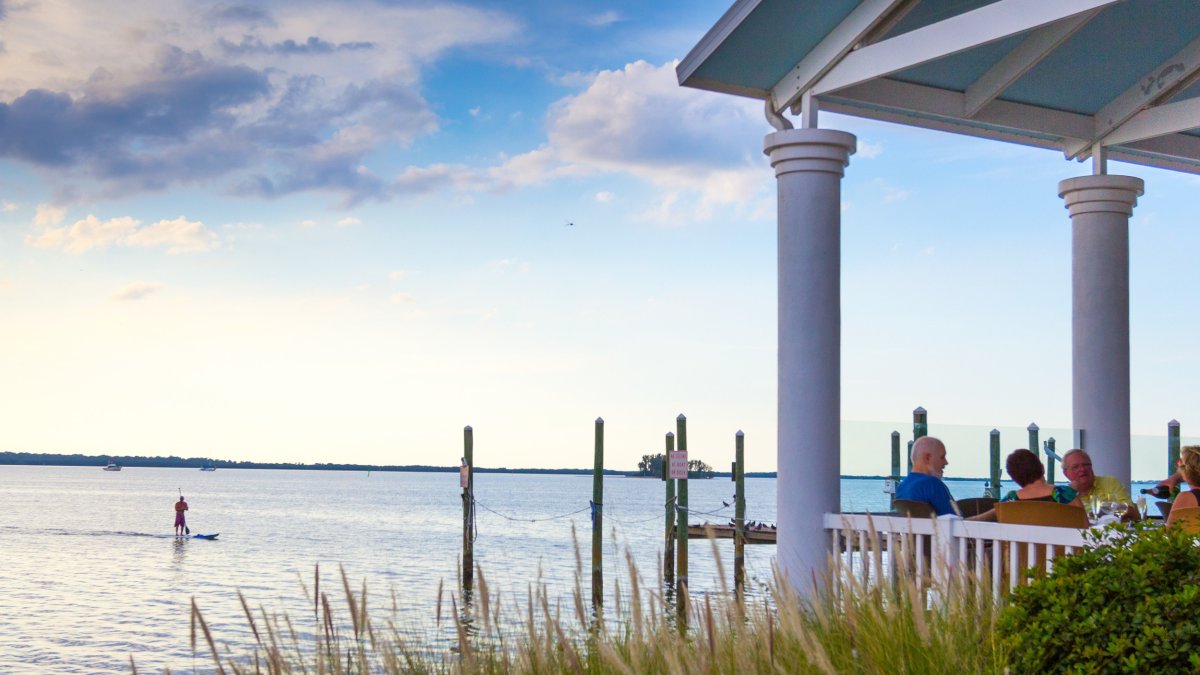 People dine on a waterfront deck at Bon Appetit in Dunedin at dusk