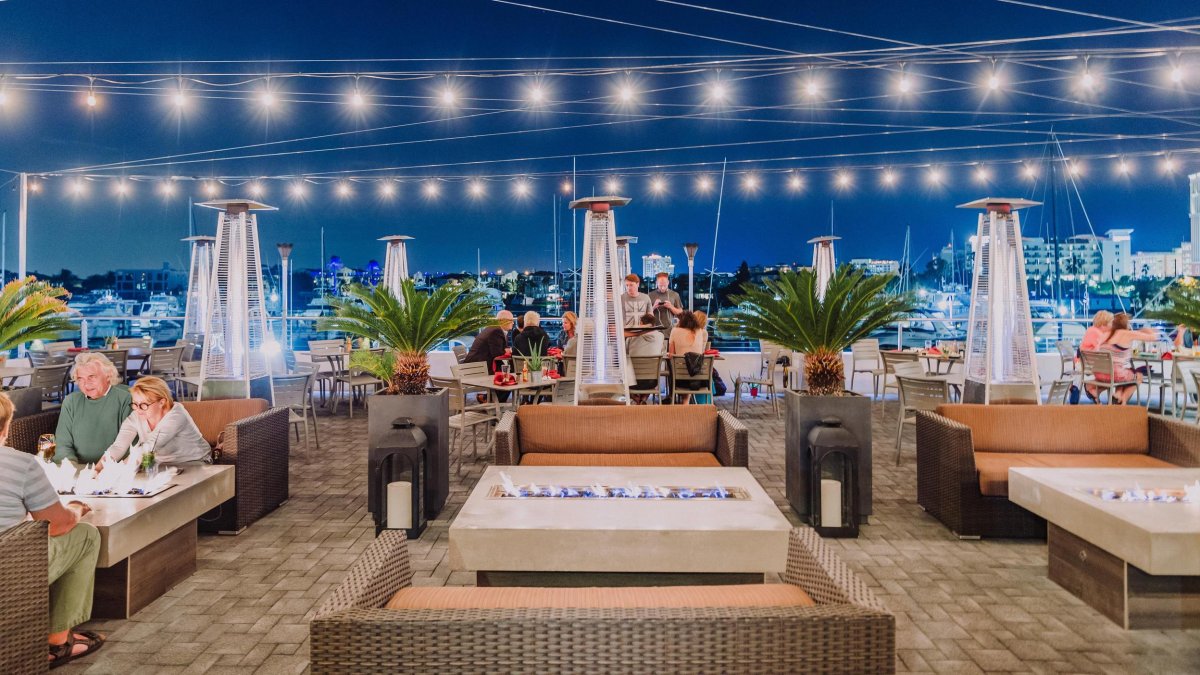 Image of outside dining area at Marina Cantina restaurant in Clearwater, FL. Featuring string lights and cushy seating for comfortable al-fresco dining.