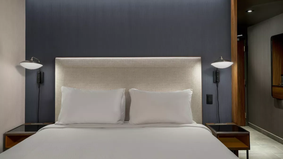 Photo of queen bed in a room at the Courtyard Clearwater Beach Marina Hotel, featuring a modern look with white sheets and pillows. 