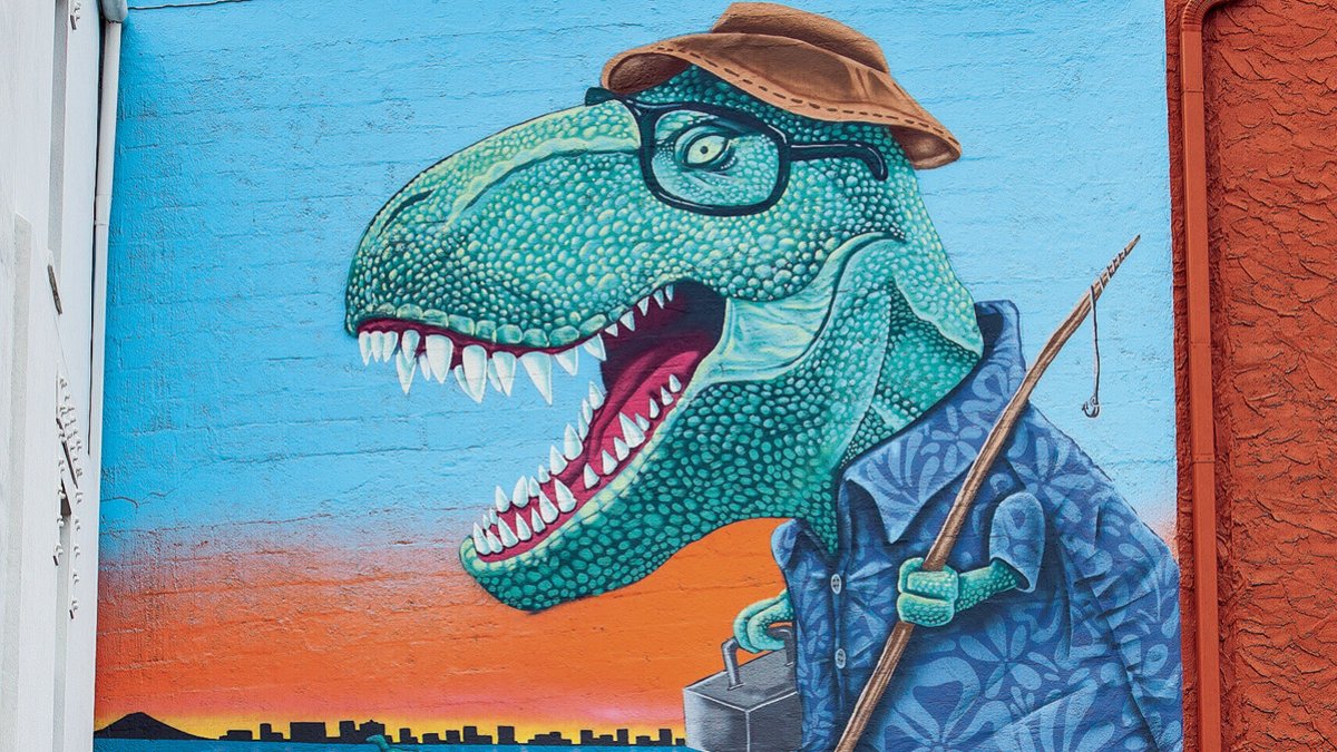 a mural depicts a tyrannosaurus rex dressed as if he is going fishing with a fishing pole, hat and tackle box. In the water behind him, a smaller dinosaur rides a jet ski