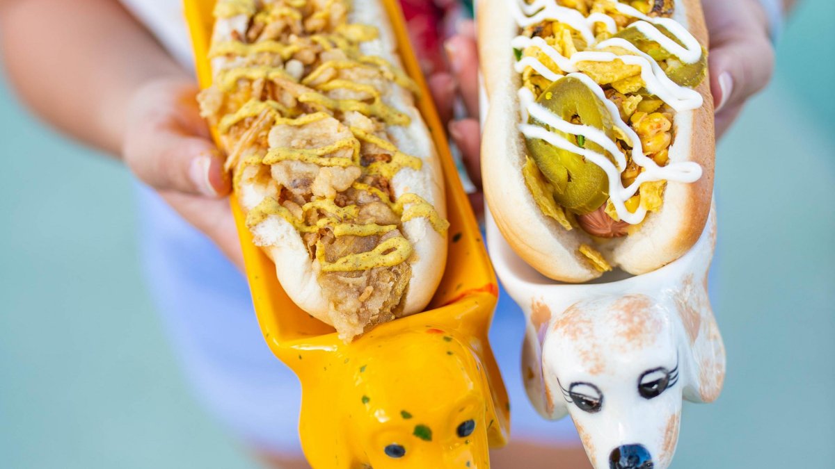 Two vegan hot dogs in cute dachshund-shaped dishes