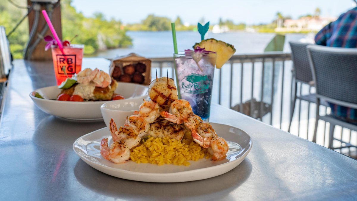 Two seafood dishes and two drinks on a bar overlooking the water at Rusty Bellies.