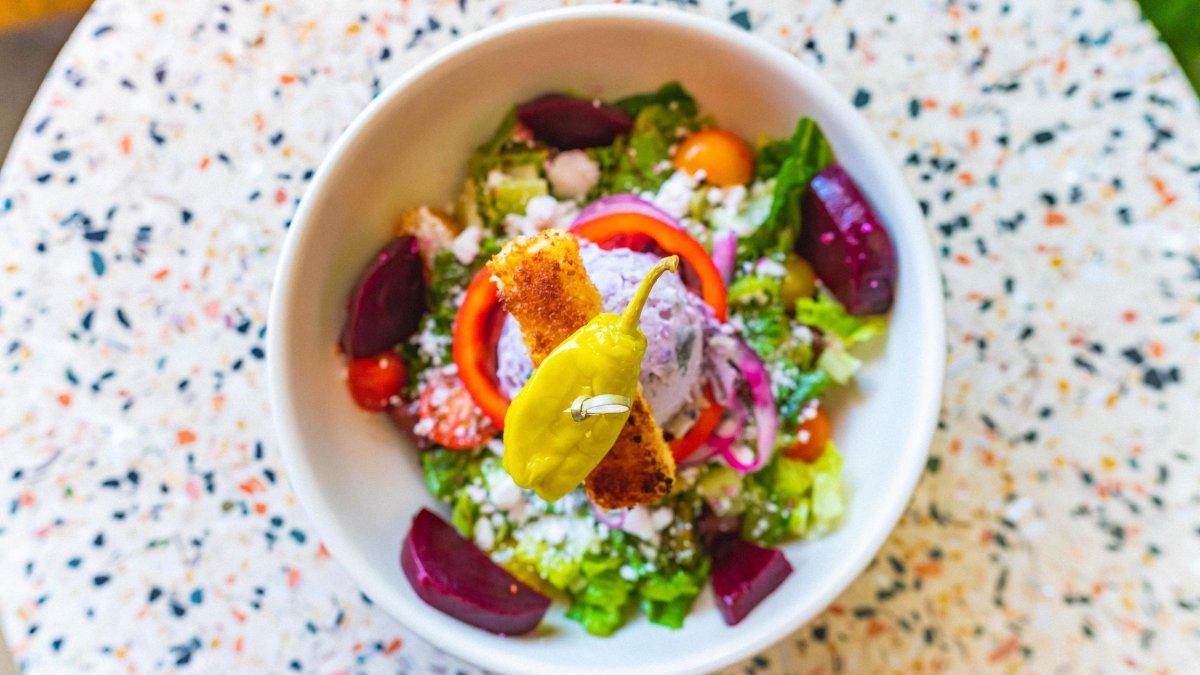 Colorful salad in a white bowl on a speckled table