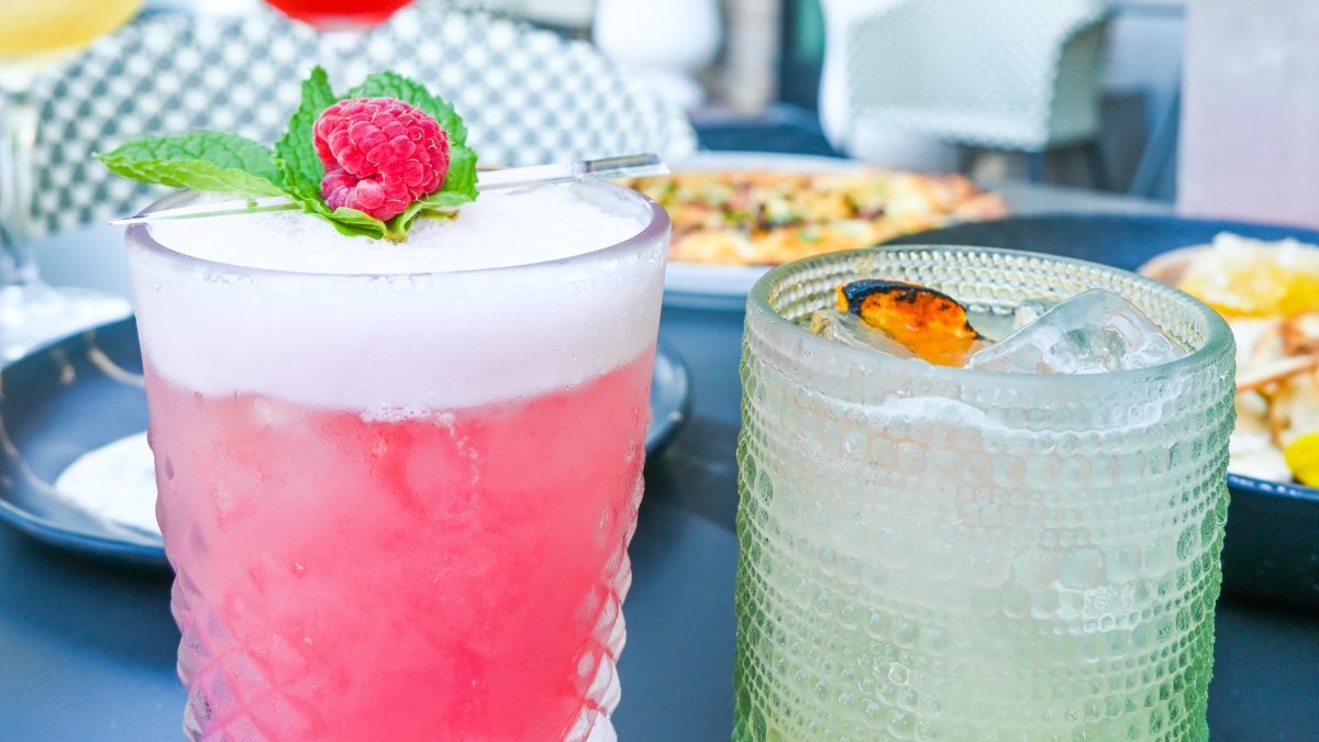 a frothy pink cocktail with a raspberry and a mint leaf next to another cocktail at the Sonder Social Club in Dunedin