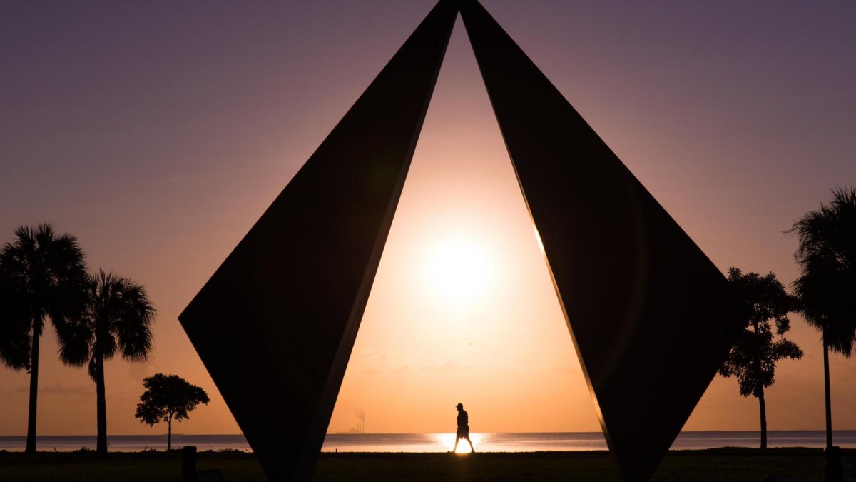a pink and gold sunrise over palm trees and the geometric Truth scuplture in Vinoy Park St. Pete