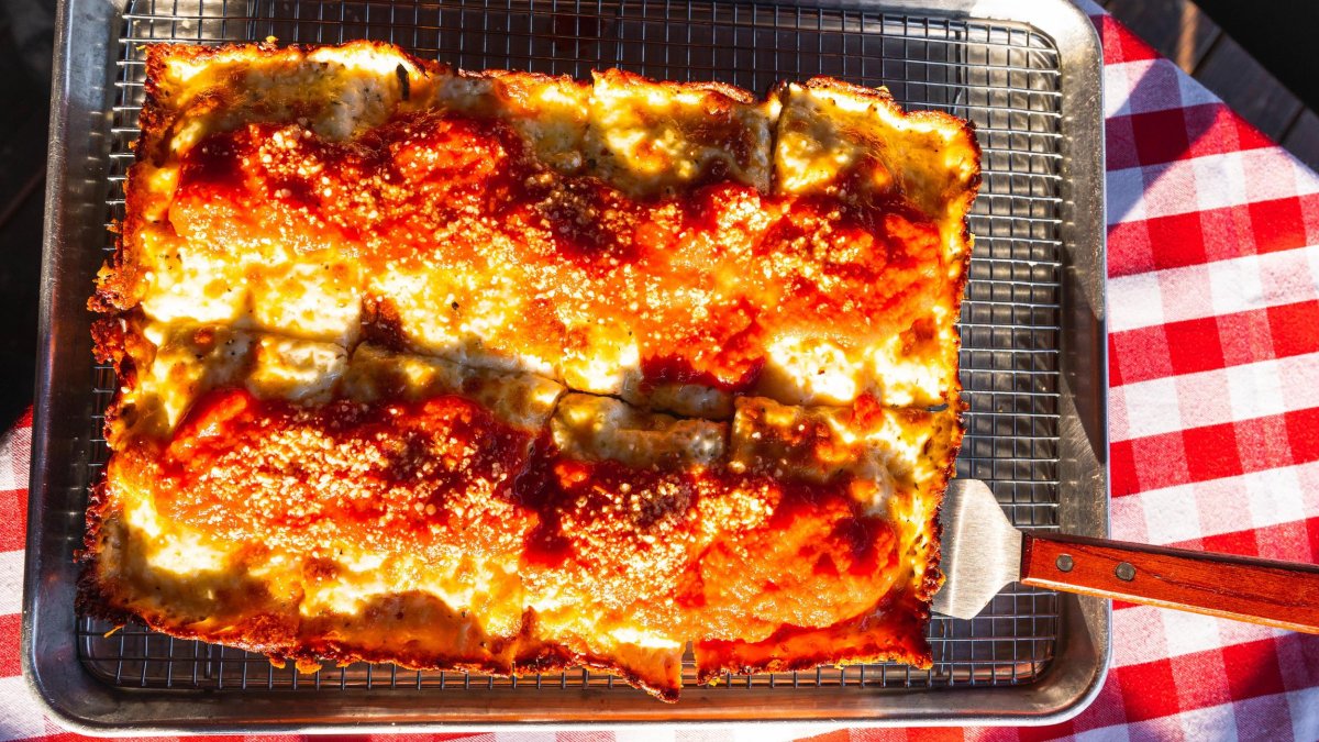 Square pizza in a pan on a red-checked tablecloth