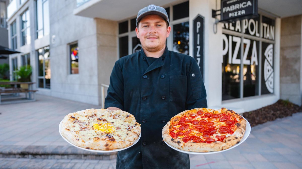 Fabrica Pizza owner holding pizzas in each hand.