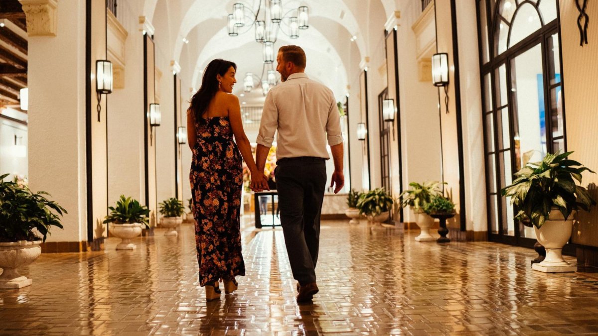 a woman and a man walk down a shiny tiled hallway with arched ceilings at the Vinoy Resort & Golf Club
